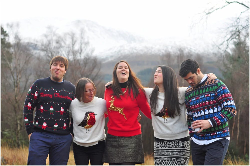 Friends in Christmas jumpers posing outdoors in front of snowy hills, captured by a Bubble event photographer