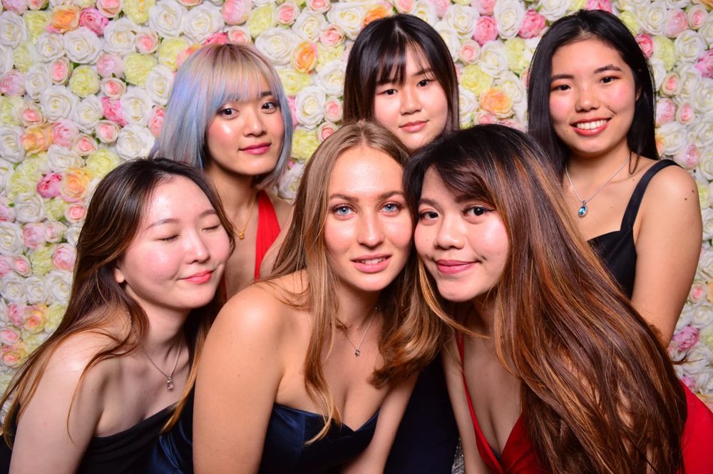Group of friends posing in front of the pastel real-flower wall photo booth