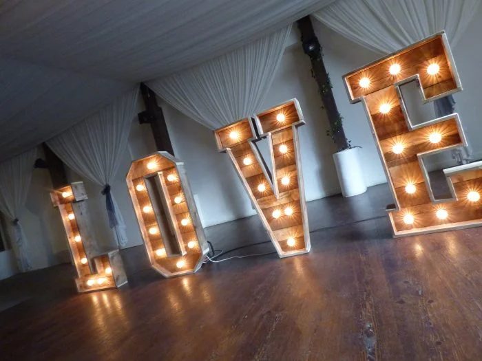Light-up LED LOVE letters on a wooden dance floor at a wedding venue
