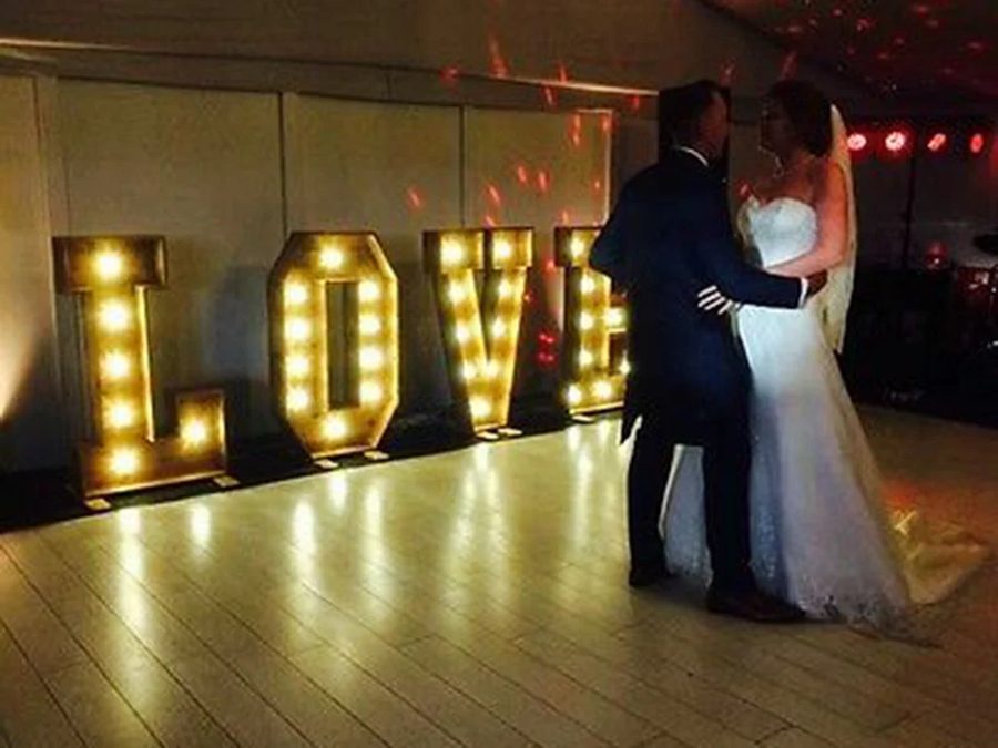 Bride and groom's first dance beside light-up LED LOVE letters