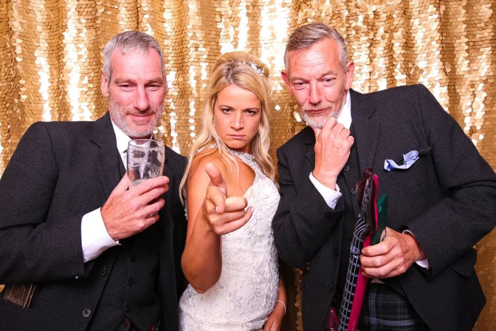 Bride and wedding guests with drinks at the open air photo booth